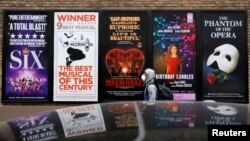 纽约曼哈顿百老汇剧院区的广告旁走过一名戴着口罩的男子。(2020年3月12日)