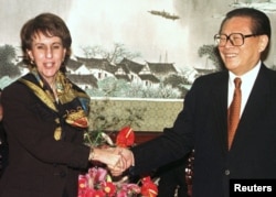 资料照片:美国贸易代表巴尔舍夫斯基与中国领导人江泽民在北京举行的WTO签字仪式上握手。(1999年11月15日)