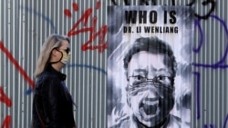 一名戴着口罩的捷克女子走过布拉格街头一幅中国眼科医生李文亮的遗像。(2020年3月27日)