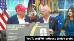 在宣布2026年世界杯足球赛的抽签仪式将于12月5日在华盛顿市的肯尼迪中心举行后,美国总统特朗普和国际足联主席因凡蒂诺在白宫展示一张世界杯门票。旁边为美国国土安全部长诺姆。(2022年8月22日)