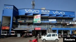 资料照:2018年12月14日,在印度艾哈迈达巴德,一名摩托车手骑过一家购物中心,旁边挂着中国智能手机制造商Vivo的广告牌,(路透社)