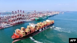 2月23日,一艘集装箱船在拖船的引导下驶入中国东部山东省青岛港的泊位。