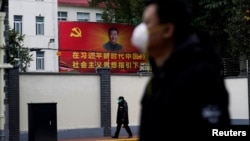 戴着口罩的行人走过上海街头习近平的画像。(2020年2月10日)
