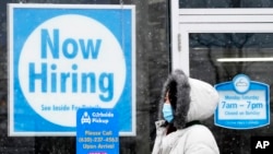 资料照片:一位女士走过伊利诺伊州绍姆堡一家清洗店的“现在招聘”标示。(2021年2月6日)