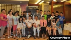 信力建(中)与部分收养的孩子(信孚教育集团网站图片)