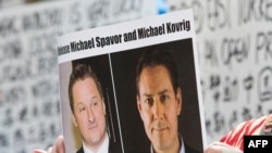 (资料照) 加拿大抗议人士举着加拿大商人迈克尔·斯帕弗(Michael Spavor)和加拿大前外交官康明凯(Michael Kovrig)的头像的标语,抗议中国政府任意拘押这两位加拿大公民。(美联社)