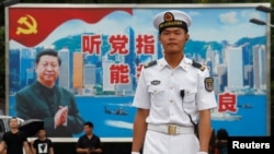 在香港海军基地,一位中国水兵站在一面具有中共党旗、习近平像和香港景象的大型看板前面(2017年7月8日)。