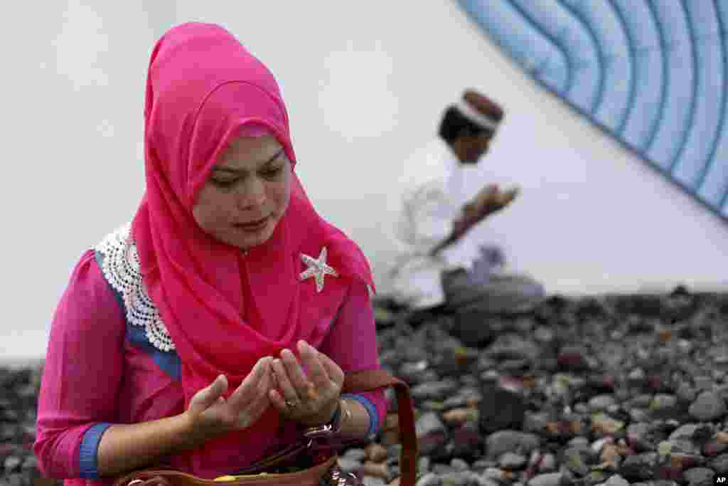 A woman mourns victims of the December 2004 Asian tsunami, praying at a mass grave in Siron, Aceh Besar, Indonesia, Dec. 26, 2014.