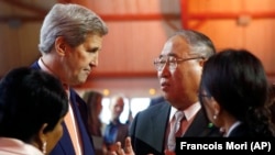 资料照片:2015年12月12日,美国时任国务卿约翰·克里(左)与中国气候变化问题特别代表解振华会谈。(美联社照片)