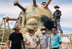 雕塑农场的“中共病毒”雕塑正在完工阶段。图为当天工作人员合影--“病毒”顶上的是赵永奎,站在架子上的是袁先生;前排左起为范先生,陈维明,苏立德和丁先生。(美国之音,2021年5月25日)