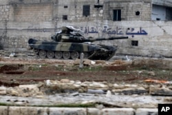 A Syrian army tank is seen in front of a wall with Arabic that reads "Aleppo is the capital of culture" in the east Aleppo neighborhood of Tariq al-Bab, Syria, Dec. 3, 2016.