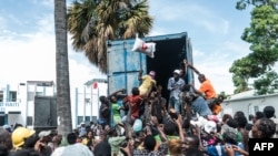 A man throws a bag of rice into a crowd of earthquake victims gathered for the distribution of food and water at the "4 Chemins" crossroads in Les Cayes, Haiti, Aug. 20, 2021.