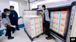 工作人员向抵达印度尼西亚的中国新冠肺炎疫苗盒子上喷洒消毒剂。(2020年12月7日)