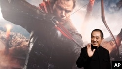 资料照:中国电影导演张艺谋在他执导的电影“长城”的广告前。