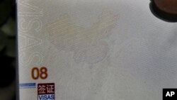 有人在北京办理护照的机构外面手持新护照,上面的地图显示南中国海属于中国