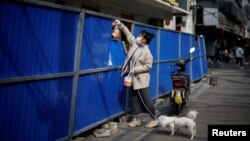 一名武汉妇女把一个食品袋递给在路障后的人。(2020年4月1日)