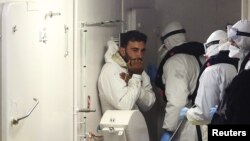 2015年4月20日一幸存移民(左)乘意大利海岸警卫队船只到意大利达卡塔尼亚