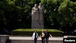 上海的一个公园里有共产主义理论家卡尔·马克思和弗里德里希·恩格斯的雕像。前面有三个人走过(2018年5月3日)。中共推崇马克思主义,限制外国学者在华研究。