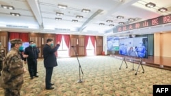 戴着口罩的中国国家主席习近平视察火神山医院时通过视频向新冠病毒感染者和医护人员招手。(2020年3月10日)