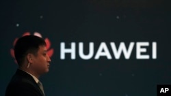 资料照片：2019年1月9日，在北京举行的华为新产品发布会上，一名保安站在华为公司标志旁。中国外交部于2019年1月11日星期五晚间表示，中国正密切关注华为员工王伟晶因涉嫌为中国从事间谍活动而被拘押的事件。