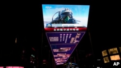 资料照片:北京一个户外屏幕上显示的一名中国战斗机飞行员在演习中竖起大拇指。(2023年4月10日)