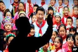 在北京展览馆前面,人们前往参观《砥砺奋进的五年》大型成就展里有中国主席习近平带着少先队的红领巾和少年儿童的合影(2017年10月23日)