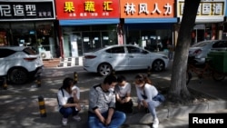 2020年5月13日,北京一个招聘服务中心外几名失业年轻人正在用手机寻找招聘信息。