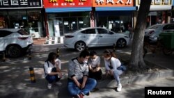 北京郊区一个招聘服务中心外几名失业的年轻人正在用手机寻找招聘信息。(2020年5月13日)