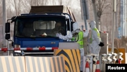 身穿防护服的警察在河北省通往北京的一个道路检查站拦住一辆卡车。(2021年1月12日)