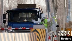 身穿防护服的警察在河北省通往北京的一个道路检查站拦住一辆卡车。(2021年1月12日)