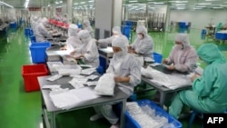 山东省滨州一家生产防护服的工厂工人在生产线上工作。(2020年2月13日)