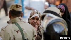 1月14日在开罗,妇女们排队准备参加公投,士兵在一旁警卫