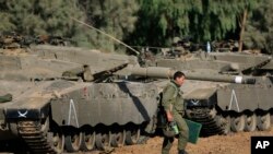 一名以色列士兵行走在停靠在以色列和加沙边界附近的坦克旁。(资料照片)