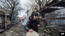 俄乌战争开战的第一天,乌克兰马里乌波尔的一名妇女逃窜经过俄罗斯炮击后的废墟。(美联社:2022年2月24日)