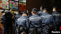 资料图:香港警察在逮捕《立场新闻》六名高管后站在该港媒办公楼外。(2021年12月19日)