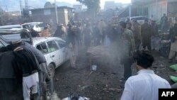 巴基斯坦安全官员和当地居民在帕拉奇纳镇一个市场的爆炸现场。帕拉奇纳镇与阿富汗接壤,是库拉姆部落地区的首府。(2017年1月21日档案照片)