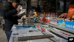 资料照:一位男士在北京一处报摊浏览谴责加拿大应美国要求拘捕华为高管孟晚舟的中国报刊。(2018年12月10日)