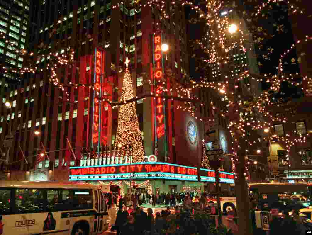 纽约无线电城音乐厅门前有巴士和游客(1997年)。 自1925年,“火箭女郎”舞蹈团就一直在这里或其他地方为“纽约客”和来自世界各地的游客献上演出。这些舞蹈演员拥有跳芭蕾舞、爵士舞和踢踏舞的经历,她们必须身材高挑,身高在168厘米到179厘米之间。