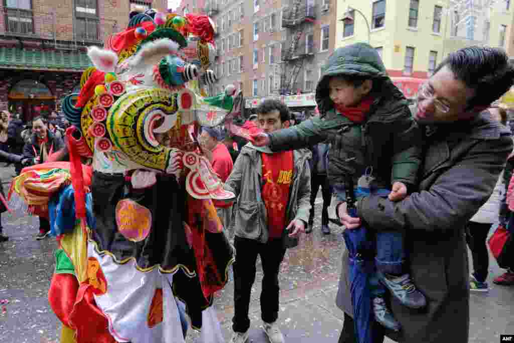 儿童给纽约中国城街头的舞龙表演者发红包（2016年2月8日）