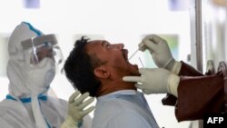 ရန်ကုန်မြို့မှာ အာဇာနည်နေ့အတွက် သတင်းယူမယ့် သတင်းထောက်တဦးကို ကိုရိုနာဗိုင်းရပ်စ် စစ်ဆေးဖို့ Swab နမူနာယူနေတဲ့ ကျန်းမာရေးဝန်ထမ်းများ။ (ဇူလိုင် ၁၆၊ ၂၀၂၀)