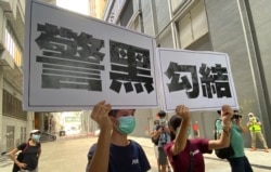 两名年轻人7月19日下午在元朗西铁站附近高举抗议警方的大型标语,他们一度被警方截查 (美国之音/汤惠芸)