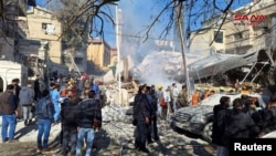 叙利亚大马士革马泽赫社区的的居民在被炸毁的一栋住宅楼废墟周围观看。