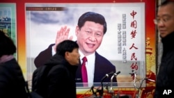 2018年3月2日,中国北京,人们走过展示中国国家主席习近平的宣传广告牌。