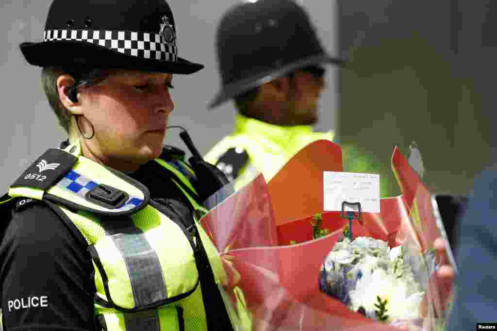 A police officer carries a bunch of flowers with a message of sympathy near Borough Market after an attack left 7 people dead and dozens injured in London, June 4, 2017.