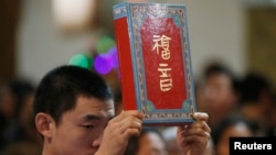 资料照:北京一家天主教堂在做圣诞弥撒时一名神职人员手举圣经。(2014年12月24日)