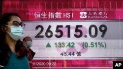一个行人走过一家香港银行的电子广告牌。2020年11月17日,香港股指因新冠疫苗的不久可望面世而上扬。