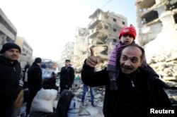People, who evacuated the eastern districts of Aleppo, stand with their belongings in a government held area of Aleppo, Syria Dec. 9, 2016.