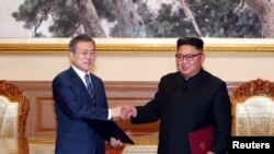 韩国总统文在寅(左)和朝鲜领导人金正恩在平壤签署《9月平壤共同宣言》后握手。(2018年9月19日)