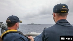 资料照片:美国海军公布的照片显示,两位美国海军中校罗伯特·J·布里格斯与理查德·D·斯莱2021年4月4日在阿利·伯克级导弹驱逐舰“马斯廷号”驾驶舱进行水面接触观察。照片中可见中国"辽宁号"航空母舰及其舷号。