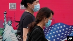 北京街头行人走过有着美国国旗和纽约自由女神画像的广告牌。(2020年8月6日)